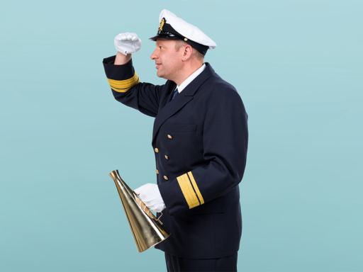 Schiffsführer Ein Mann in nautischer Uniform und mit einem Sprechtrichter in der Hand schaut in die Ferne.